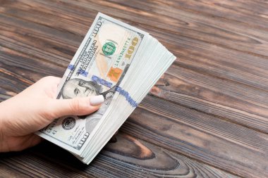 Ahşap arka plan üzerinde yüz dolarlık banknotlar veren kadın el Perspektif görünümü. Kopyalama alanı ile sadaka ve bağış kavramı