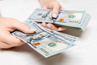 Kadın el ahşap arka plan üzerinde yüz dolarlık banknotlar veriyor. Zenginlik kavramına bakış açısı