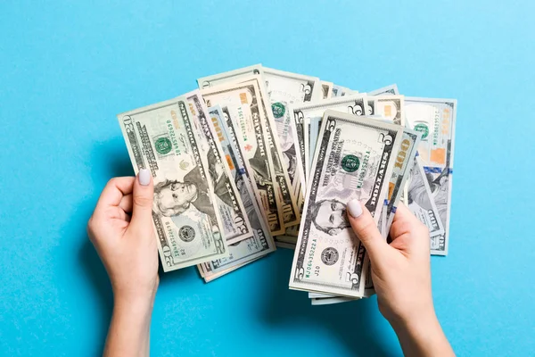 V rukou obchodovaných žen se počítá s pěti a dalšími dolarovou bankovkami na barevném pozadí. Koncept platů a mezd. Pohled shora na investiční koncept — Stock fotografie