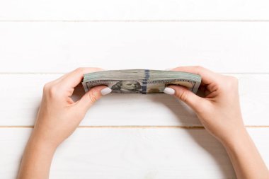 Ahşap arka planda kadın elinde yüz dolarlık banknotlar demeti. Finans ve iş kavramı