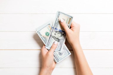 Kadın el ahşap arka plan üzerinde yüz dolarlık banknotlar veriyor. Zenginlik kavramının en iyi görünümü