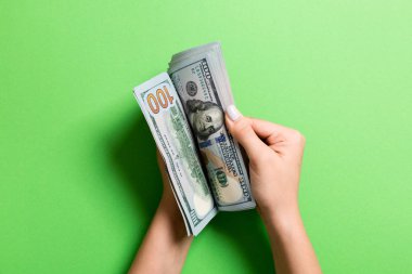İş kadınının elleri renkli arka planda 100 dolarlık banknotları sayıyor. Maaş ve ücret kavramı. Yatırım kavramına en üst düzey bakış