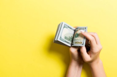 İş kadınının elleri renkli arka planda 100 dolarlık banknotları sayıyor. Maaş ve maaş kavramı kopyalama alanı ile. Yatırım kavramına en üst düzey bakış