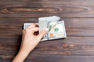 Kadın eli para sayıyor. Ahşap arka planda 100 dolarlık banknotlar. İş konsepti