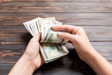 Para sayan kadın ellerinin perspektif görünümü. Ahşap arka planda 100 dolarlık banknotlar. Maaş kavramı. Rüşvet kavramı