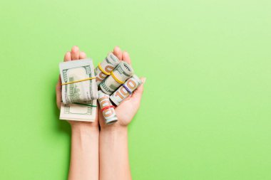 Renkli arka planda kadın avuç içi tüpler dolar banknotları rulo üst görünümü. Tasarım için boş alan ile yoksulluk ve borç kavramı