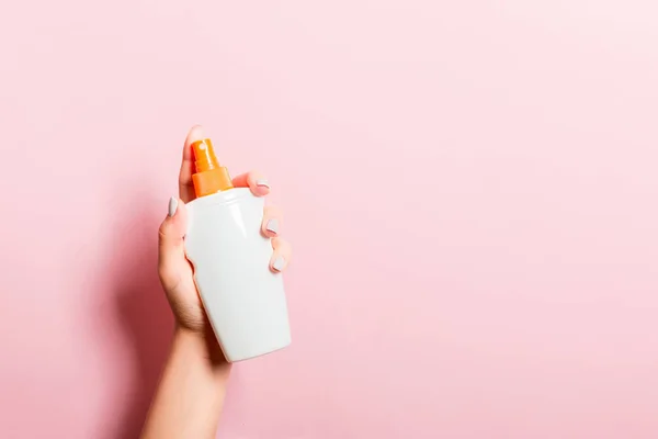 Frasco de crema pulverizadora de mano femenina de loción aislada. Chica dar productos cosméticos sobre fondo rosa —  Fotos de Stock