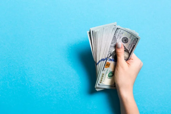 Vista superior de la mano femenina sosteniendo un paquete de billetes de cien dólares sobre un fondo colorido. Concepto salarial y salarial con espacio vacío para su diseño — Foto de Stock