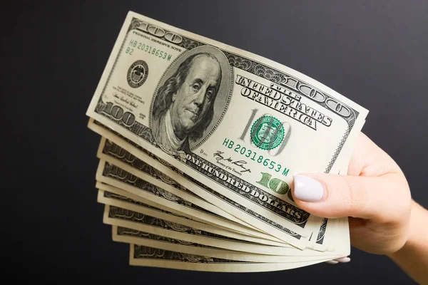 Ventilatore di banconote da cento dollari in mano femminile su sfondo colorato. Concetto di investimento — Foto Stock