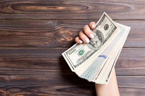 Ahşap arka plan üzerinde kadın elinde farklı dolar banknotlar Kalın demet. Finans ve iş kavramı