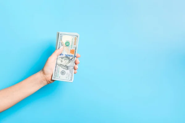 Dollarnoten in weiblicher Hand auf blauem Hintergrund. Geschäftskonzept — Stockfoto