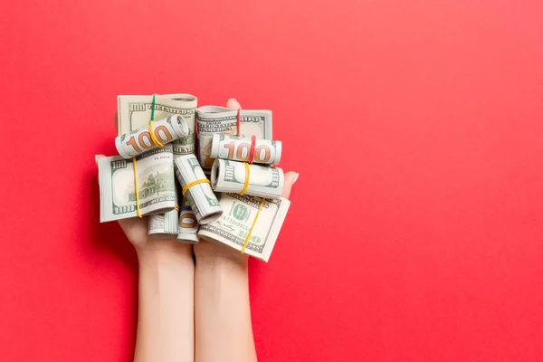 Vista superior de enrollado en billetes de dólares tubos en palmas femeninas sobre fondo colorido. Concepto de pobreza y deuda con espacio vacío para su diseño — Foto de Stock