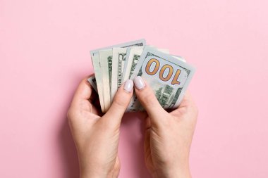 Renkli arka planda bir deste para tutan bir kadının üst görüntüsü. Çeşitli dolarlar. İş konsepti. Hayırseverlik ve bahşiş kavramı