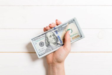 Femle elinde 100 dolarlık banknotlar. Renkli arka planda para tasarrufu konseptinin en iyi görünümü