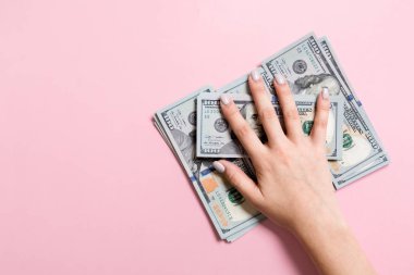 100 dolarlık banknotyığının üzerinde yatan kadın ellerinin en iyi görüntüsü. Renkli arka planda başarı ve zenginlik kavramı