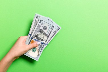 Renkli arka planda yüz dolarlık banknotlar veren kadın elinin üst görünümü. Kopyalama alanı ile sadaka ve bağış kavramı