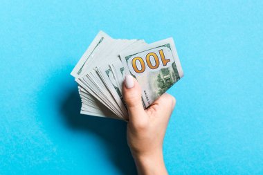 Renkli arka planda bir paket para tutan kadın elin üst görünümü. Yüz dolar. İş konsepti. Sadaka ve ipuçları kavramı