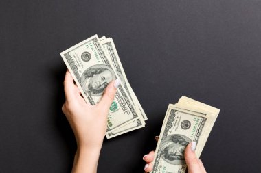 Kadın eli biraz para veriyor, 100 dolarlık banknotları yakın plan sayıyor. Renkli arkaplan üzerine iş kavramı