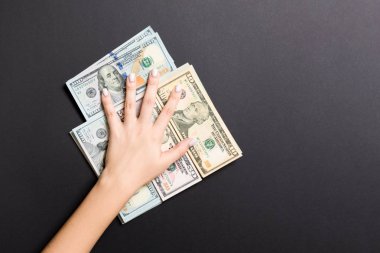 Kadın el renkli arka plan üzerinde çeşitli dolar banknotları yığını üzerinde yalan. Para tasarrufu ve refah kavramı