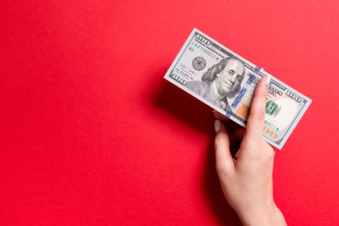 Renkli arka planda yüz dolarlık banknotlar veren kadın elinin üst görünümü. Kopyalama alanı ile sadaka ve bağış kavramı