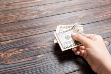 Ahşap arka planda kadın elinde 10 ve 50 dolarlık banknotlar. Kopya alanı ile maaş kavramı