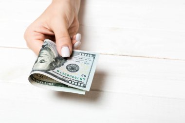 Ahşap arka planda kadın elinde yüz dolarlık banknotlar bir paket. Kopya alanı ile maaş kavramı