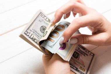 Para sayan kadın ellerinin perspektif görünümü. Renkli arka planda yüz dolar banknotlar. İş kavramı