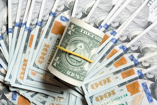Horní pohled na 1 válcované dolarové bankovky na pozadí vyrobené se stodolarovými bankovkami. Obchodní koncept — Stock fotografie