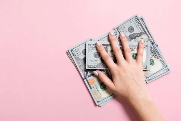 Pohled na ženské ruce ležící na hromadě 100 dolarových bankovek. Koncepce úspěchu a bohatství na barevném pozadí — Stock fotografie