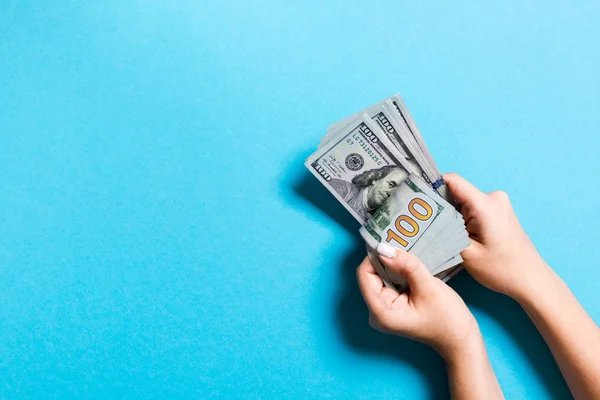 Pohled na ruku businessovy ženy počítá 100 dolarových bankovek na barevném pozadí. Koncepce úspěchu a bohatství s prostorem kopírování — Stock fotografie
