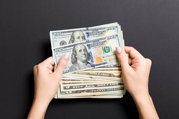 Vista superior de diferentes billetes de dólar en manos femeninas sobre un fondo colorido. Concepto empresarial y financiero — Foto de Stock