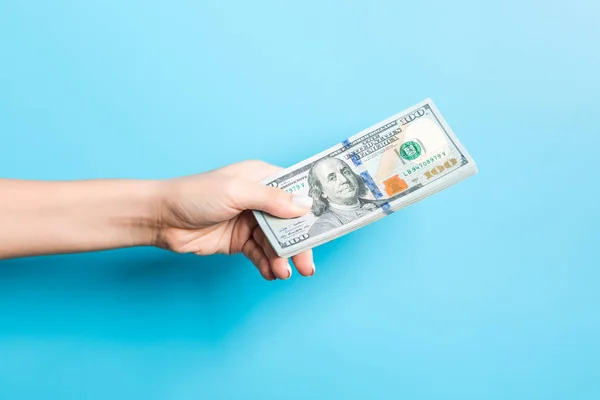 Ženská ruka dává balík dolarových bankovek na modrém pozadí. Koncepce moci a bohatství — Stock fotografie