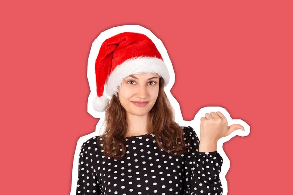 Портрет женщины в платье, указывающий влево большим пальцем и смущенный. эмоциональная девушка в рождественской шляпе Санта Клауса изолирована на белом фоне. Концепция отдыха — стоковое фото