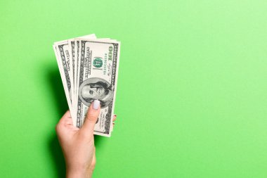 Kadın el renkli arka plan üzerinde para bir demet tutan. 100 dolarlık banknotların en iyi görünümü. Tasarım için boş alan ile Maaş kavramı