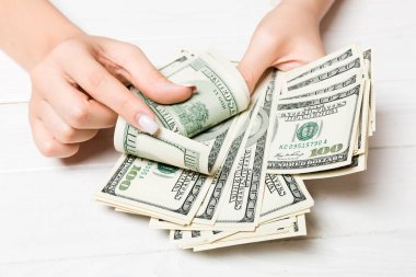İş kadınının elleri ahşap zeminde 100 dolarlık banknotları sayıyor. Maaş ve ücret kavramı. Yatırım kavramına en üst düzey bakış