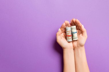 Renkli arka planda kadın avuç içi dolar banknotları kadar haddelenmiş. Yoksulluk ve kötü kavram