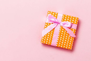 Pembe arka planda pembe kurdeleli el yapımı Noel hediyeleri. Şimdiki kutu, renkli tabloda hediye süslemesi, kopya alanı ile üst görünüm