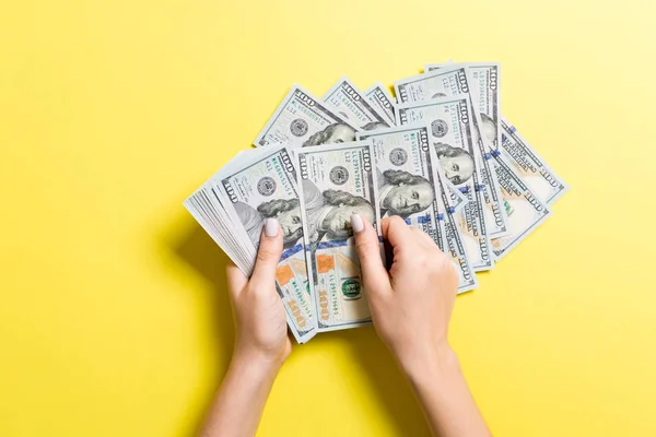 Vista dall'alto delle mani femminili che contano i soldi. Banconote da cento dollari su sfondo colorato. Concetto di stipendio. Concetto di corruzione — Foto Stock