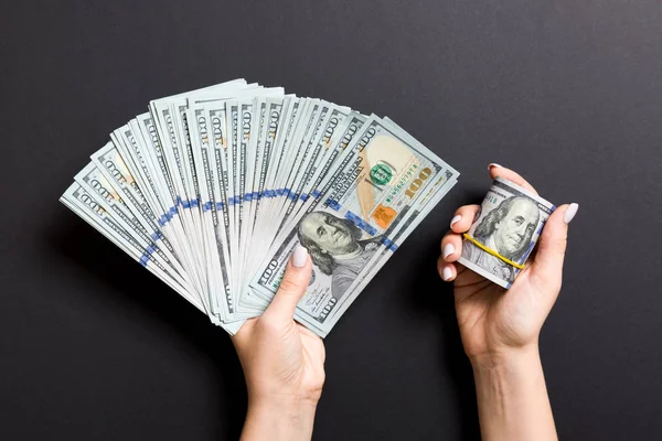 Renkli arka planda yüz dolar bir fan tutan kadın el üst görünümü. Kredi konsepti. Refah kavramı