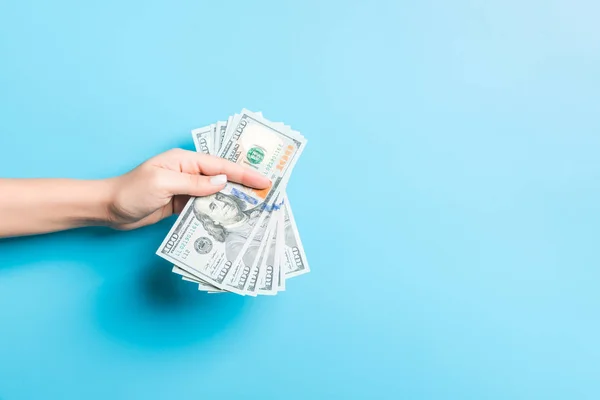 Ženská ruka dává peníze na modré pozadí. Dolarové bankovky. Koncept úplatku. Koncepce dluhu a úvěru — Stock fotografie