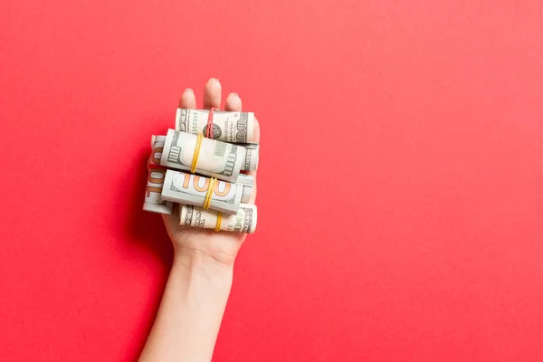 Bovenaanzicht van dollarbiljetten in tubes in vrouwelijke hand op kleurrijke achtergrond. Bedrijfsconcept — Stockfoto