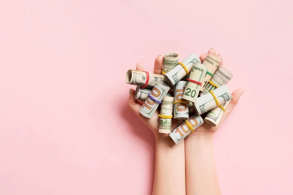 Pohled shora na ženské ruce držící hodně srolovaných dolarových bankovek na barevném pozadí. Chudoba. Koncept úvěru — Stock fotografie