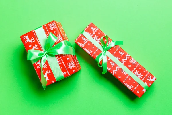 緑の背景に緑のリボンで紙にクリスマスや他の休日の手作りプレゼントを包んだ。プレゼントボックス、カラーテーブルのギフトの装飾、トップビュー — ストック写真