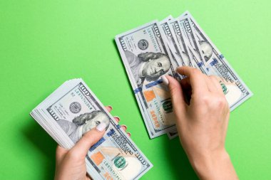 Renkli arka planda yüz dolarlık banknotlar sayan bir iş kadınının ellerinin en iyi görünümü. Başarı ve zenginlik kavramı