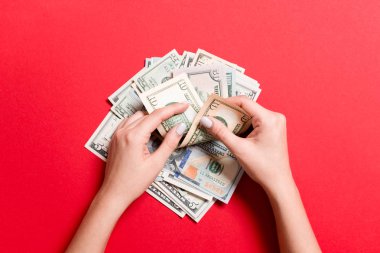 Para sayan kadın ellerinin en iyi görünümü. Renkli arka plan üzerinde çeşitli dolar banknotlar. Maaş kavramı. Rüşvet kavramı