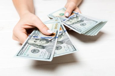 Kadın el ahşap arka plan üzerinde yüz dolarlık banknotlar veriyor. Zenginlik kavramına bakış açısı