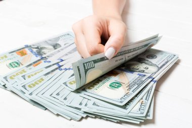 İş kadınının elleri ahşap zeminde 100 dolarlık banknotları sayıyor. Maaş ve ücret kavramı. Yatırım kavramına en üst düzey bakış