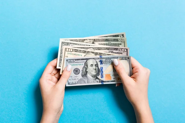 Vista superior de diferentes billetes de dólar en manos femeninas sobre un fondo colorido. Concepto empresarial y financiero — Foto de Stock
