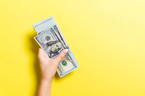 Paquete de billetes de cien dólares en mano femenina sobre fondo colorido. Concepto financiero y empresarial con espacio de copia — Foto de Stock