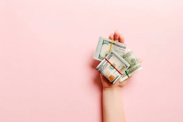 Top view of dollar bills in tubes in female hand on colorful background. Business concept — Stock Photo, Image